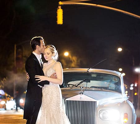 Bride and groom in front of 1963 Rolls Royce on 5th Ave, NYC after a wedding reception and rain. Allure Couture
