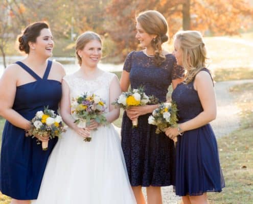 Bride holding yellow, mauve, grey and moss green fall wedding bouquet stands with bridesmaids wearing navy blue dresses in this Bernards Inn fall wedding party portrait