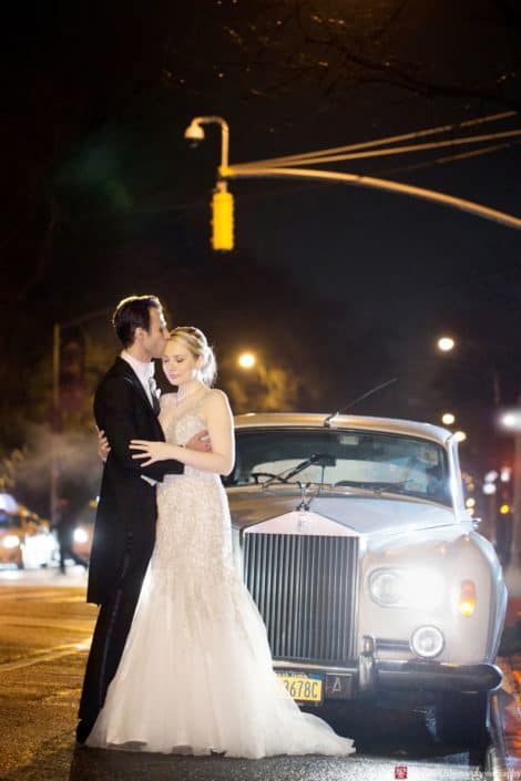 Bride and groom embrace in front of a 1955 Rolls Royce for an evening wedding photo in NYC at the Lotos Club. Lotos Club Wedding Photography by Kyo Morishima. Allure Couture wedding gown.