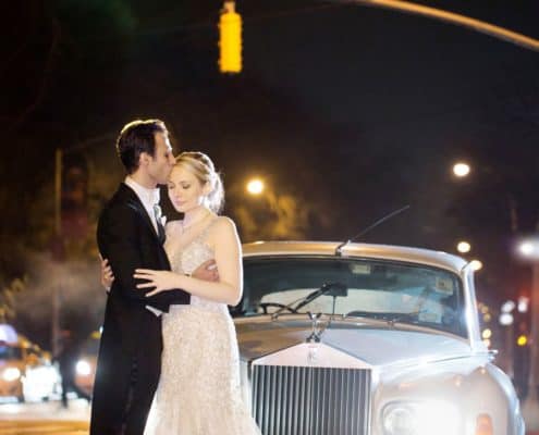 Bride and groom embrace in front of a 1955 Rolls Royce for an evening wedding photo in NYC at the Lotos Club. Lotos Club Wedding Photography by Kyo Morishima. Allure Couture wedding gown.