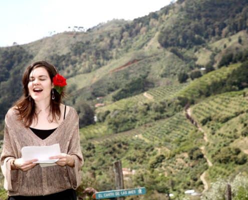 Wedding guest give speech at Talamanca cloud forest wedding ceremony, green mountainside, red rose tucked behind woman's ear. Costa Rican destination wedding photographer.