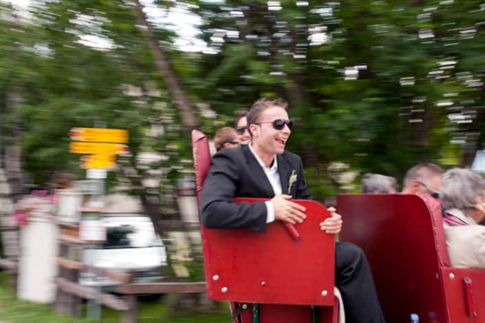 Wedding guests take a ride on red seats in Swiss Alps for European destination wedding photography. Motion photography.