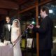 Guest gives speech at destination wedding in Kyoto, Japan, Garden Oriental, now called The Sodoh Higashiyama Kyoto, as bride and groom look on, Bride wears elegant white wedding dress with ruched bodice. floor to ceiling windows, pink and white bouquet.