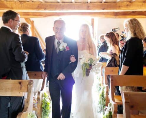 Bride walks down aisle with her father at tiny Romanesque church in the Swiss Alps. European destination wedding photographer, Swiss Alps. Gardenias Floral.
