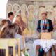 Bride and groom listen as officiant performs wedding ceremony at European destination wedding in a tiny Romanesque church in the Swiss Alps. Aged painted wall mural background.