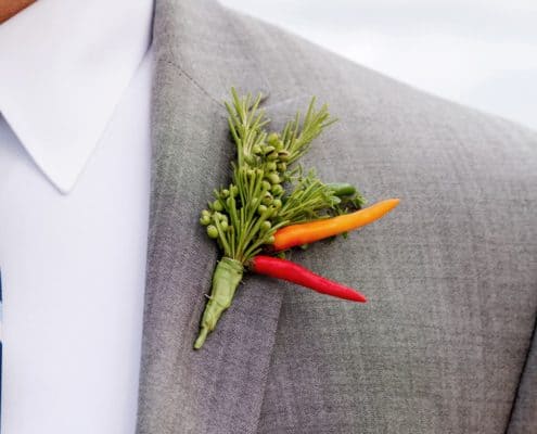 green foliage with red and orange pepper boutineer on gray suit, Dahlias Florist, Spring Lake NJ wedding photographer.