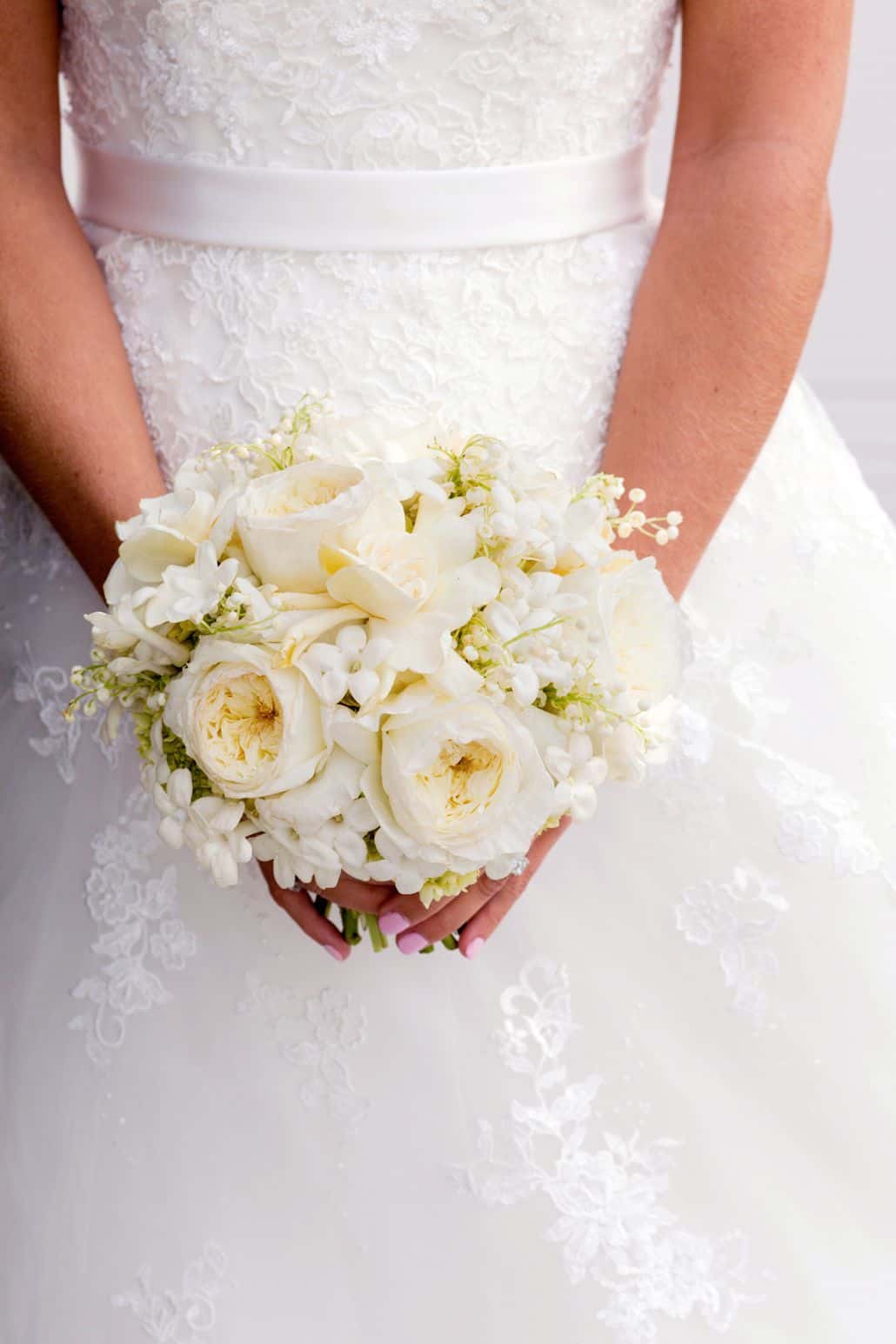 white and cream bridal bouquet held by bride wearing lace and tulle gown with white satin sash, Dahlia's Florist, Spring Lake NJ wedding photographer.