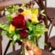 deep red, bright yellow, pink and green wedding bouquet, roses, peonies, peach ribbon, standing on dark wooden chair, Kristin Rockhill florsit, Nassau Inn, Princeton NJ wedding photographer.