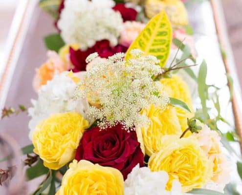 Yellow and red long narrow table centerpiece. red roses, red dahlias, white hydrangea, tropical leaves, quenn anne's lace, silver platter, Kristin Rockhill florist, Nassau Inn, Princeton NJ wedding photographer.