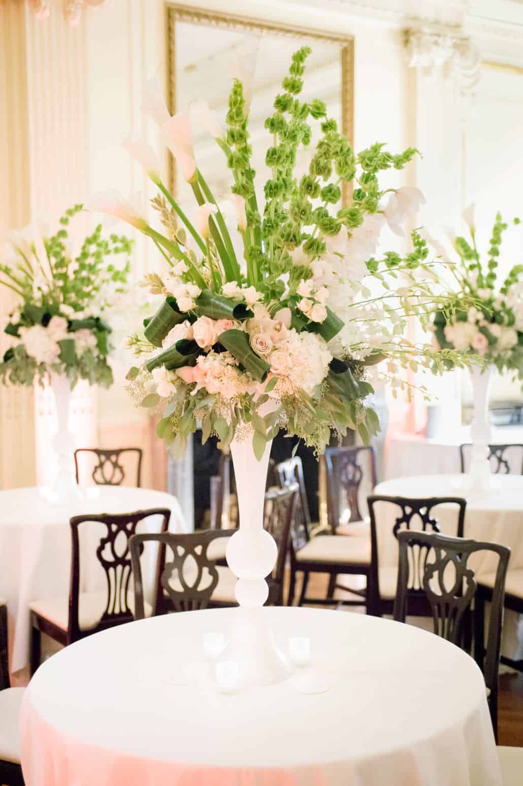 tall peach and green wedding table centerpieces with roses, bells of ireland, calla lilies, eucalyptus, hydrangea at lotos club NYC, Franz James florist, black dining chair and white table cloths with tea lights. New York Wedding photographer.