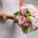 pink and white rose and peony bridal bouquet with green accents held out by bride, white and gold bracelet, Etsuko Planning, River cafe brookly NY wedding photographer.