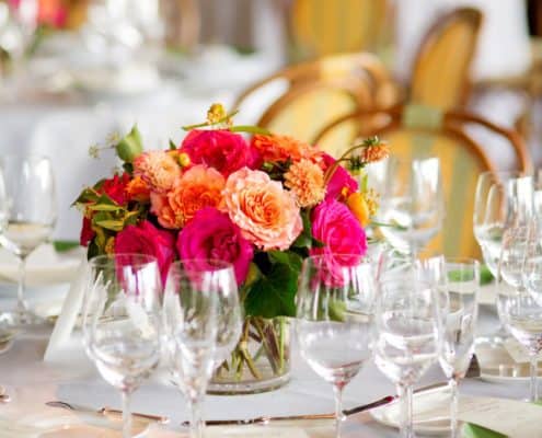 fuscia orange and green wedding table centerpiece, leaf green rimmed plates, white napkins, clear stemware, Etsuko Planning, River Cafe Brooklyn NY wedding photographer.