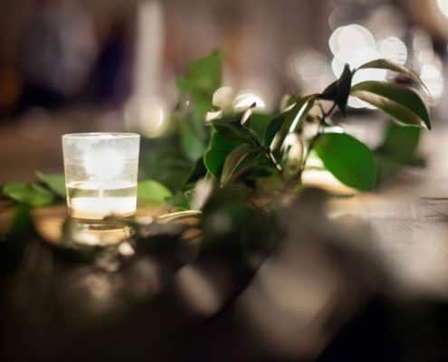close up wedding photo of tea light candle and green foliage at the green building in brooklyn NY. Evening wedding photography, new york wedding photographer. flower wholesaler, flower district, manhattan. DIY wedding flowers.