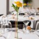 Single stem flower stand, copper arm, white base, yellow flower, white table linens, clear stemware, Karen Brown Events NYC wedding photographer.