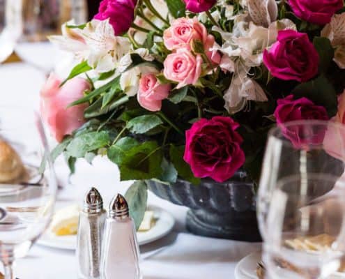 pink, fuscia, white and green rose wedding flower centerpiece in dark gray antiqued bowl, gold flatware, white linens, Karen Brown Events NYC wedding photographer.