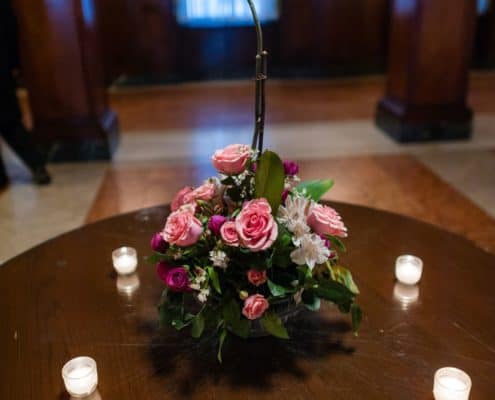 white orchid in center of pin and fuscia wedding centerpiece on dark wood table with tealights. Formal dark wood wall paneling, Karen Brown Events NYC wedding photographer.