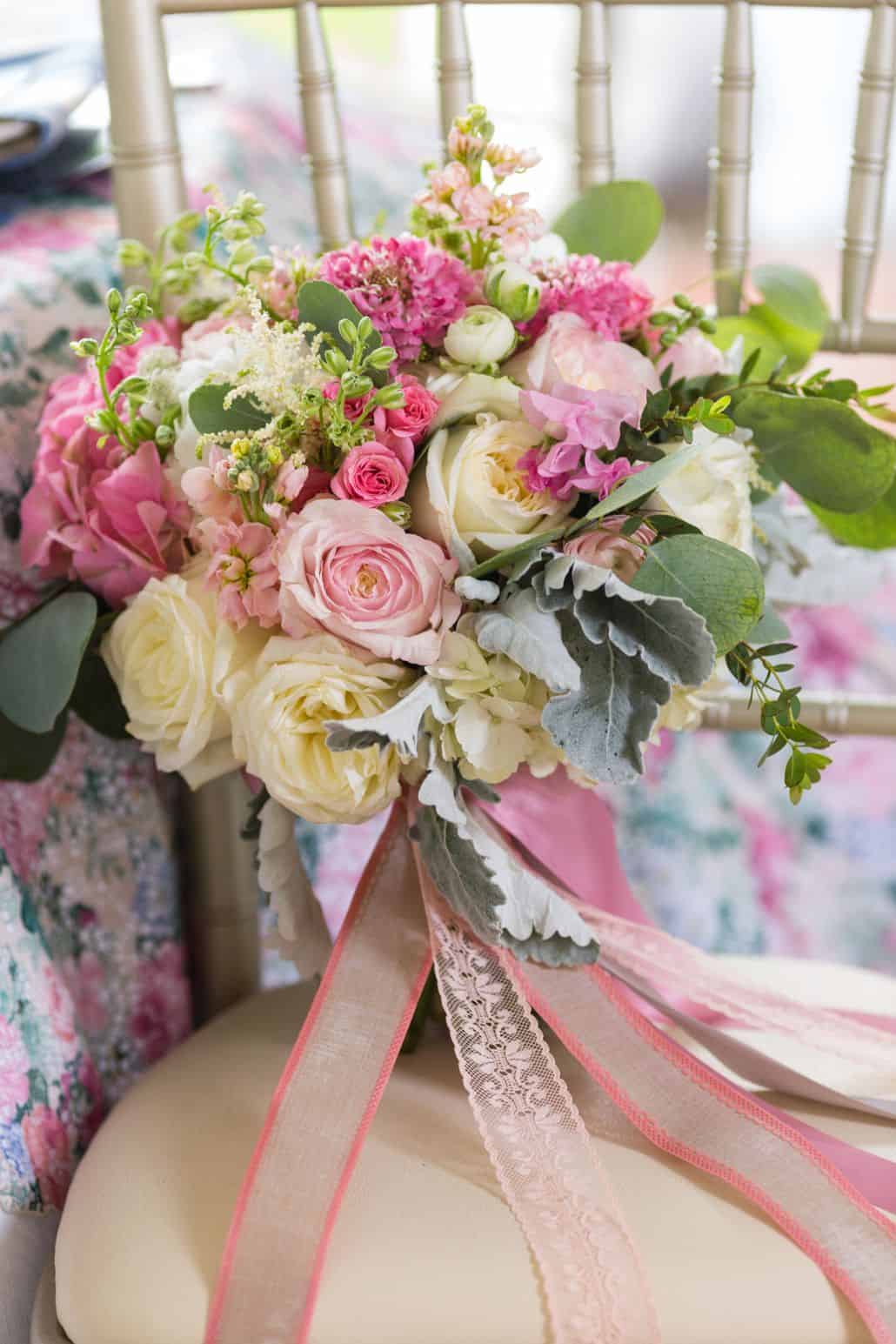 Pink, cream and sage bridal bouquet trailed by pink and cream lace ribbon on silver chiavari chair. Kristin Rockhill florist, Chauncey center Princeton, NJ wedding photographer