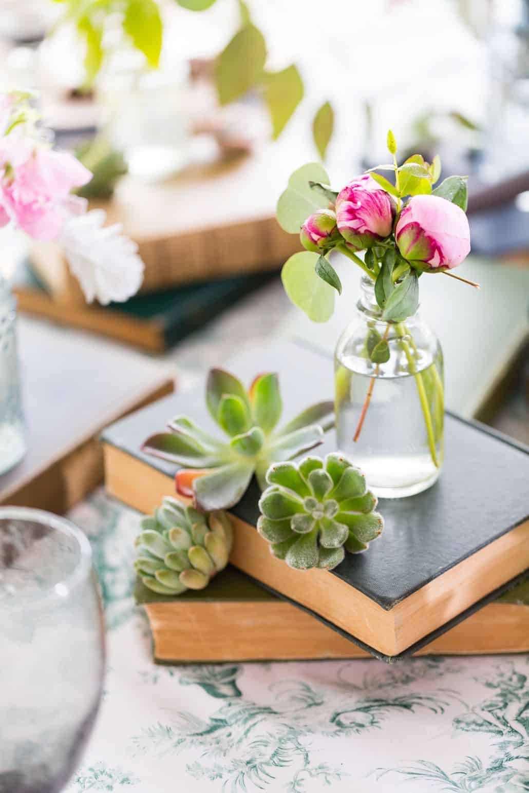 pink flower buds in bud vase on stacked books surrounded by succulents at Chauncey Center wedding in Princeton, NJ. Kristin Rockhill florist, New Jersey wedding photographer.