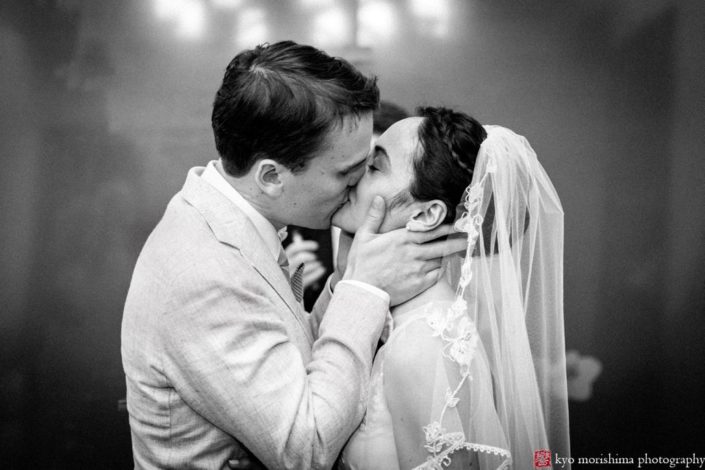 black and white photo of bride and groom's first kiss as man and wife. Bride's hair braided crown. NYC City Hall elopement photographer. Summer NYC wedding photo.