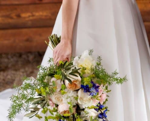 bride holds pink and white bridal bouquet with blue accents at her side at Blooming hill farm in Blooming Grove New York, Fleur di Re florist, New York wedding photographer.