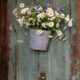 daisies in a metal bucket hung on an old chipped paint door at blooming hill farm NY, Fleur di Re florist, New York wedding photographer.