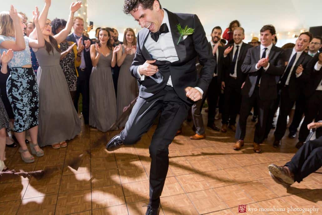 groom enthusiastically dances while guest form a circle around him at Blooming Hill Farm Jewish wedding. NYC June wedding photographer. Cartwright tent. Kyo Morishima Photography