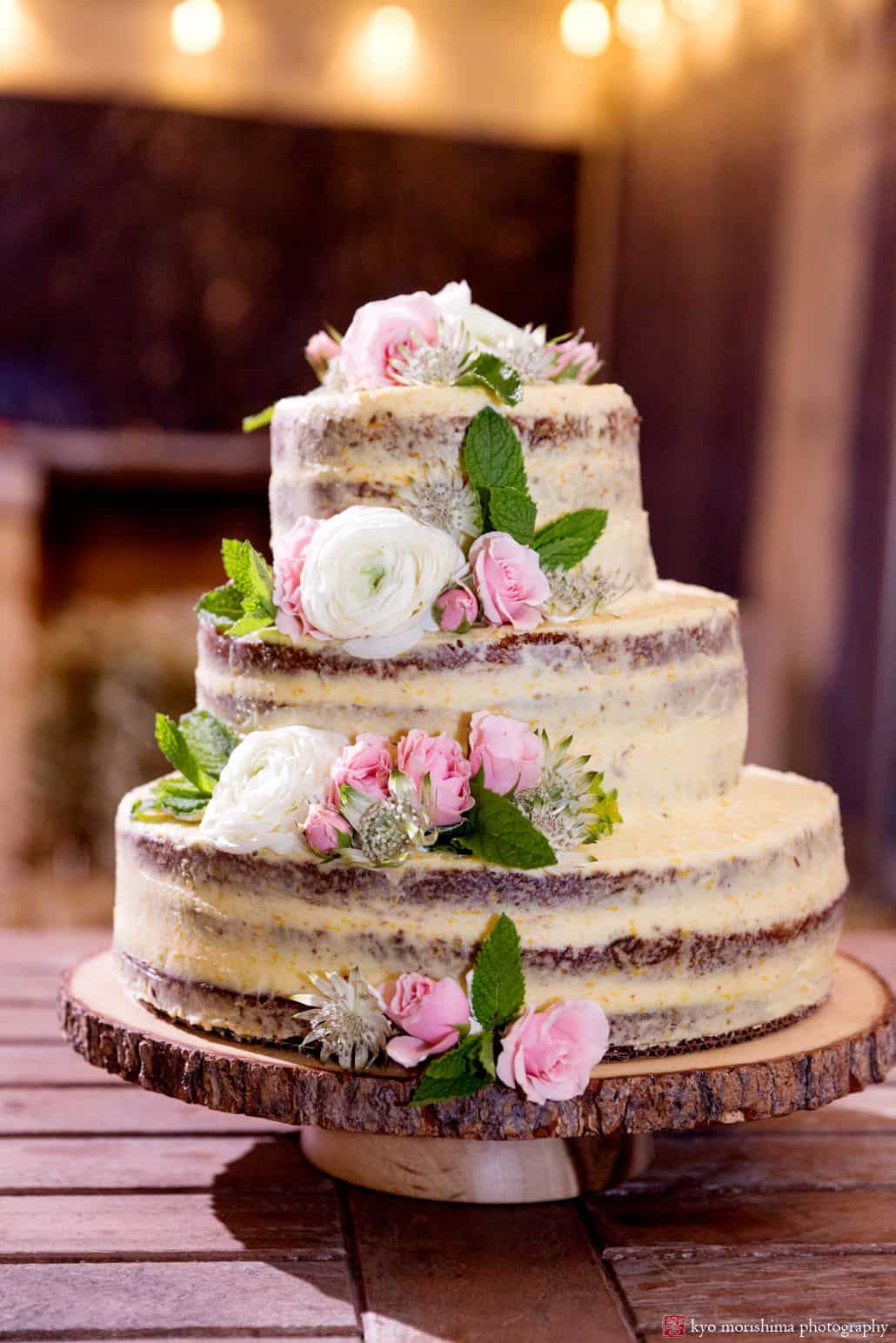 Rustic naked wedding cake by the village tea room NYC at blooming hill farm wedding. wooden cake stand, orange zest frosting, pink roses and white ranunculus and mint leaves wedding flowers, fleur di re florist, three tier wedding cake, NYC Summer wedding photographer. Hudson Valley Kyo Morishima Photography