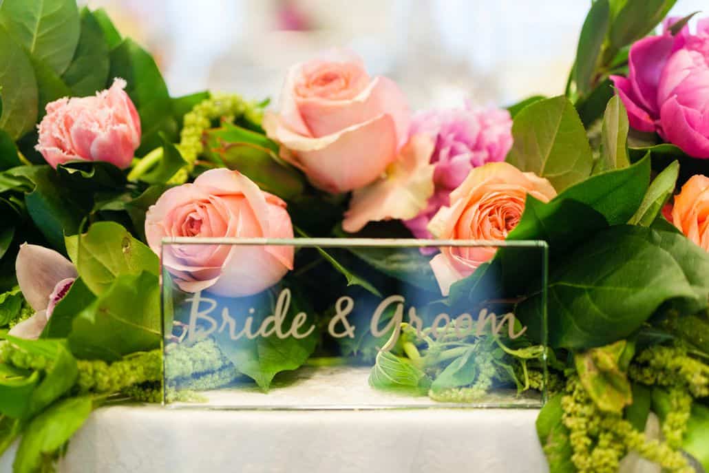 clear bride & groom plaque amongst roses, tulips, peonies and orchids, peach and fusica wedding table floral arrangements, Kristin Rockhill florist, Nassau Inn, Princeton NJ wedding photographer.