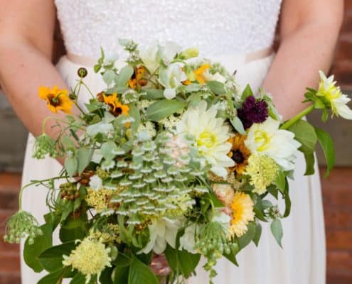 Bride with beaded lace bodice gown holds whimsical wildflower bridal bouquet, Jenn Florin Florist, Brooklyn Grange, Brooklyn Navy Yard, Brooklyn wedding photographer.