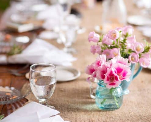 pink canterbury bells and fuscia center flowers in turquoise mug and small mason jar on burlap table runner and dark wood table, white napkins, Stem Cut Flowers florist, Lake Geneva, WI wedding photographer.