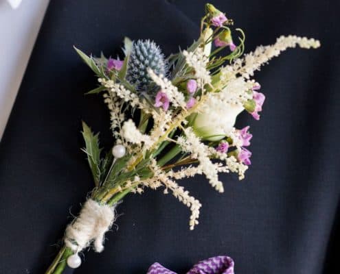 blue sea holly, white astilbe and pink flower boutineer wrapped in white twine, white and purple pocket square, Flower Muse wholesaler, Krystle De Santos wedding designer, Metropolitan Building, Long Island City, NY wedding photographer.