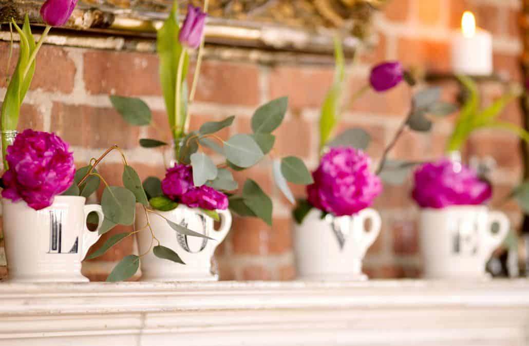 fuscia peonies and silvery leaves in white mugs that spell L O V E, fuscia tulips in bud vases on white mantle in front of brick wall, Flower Muse wholesaler, Krystle De Santos event designer, Metropolitan Building, Long Island City, NY wedding photographer.
