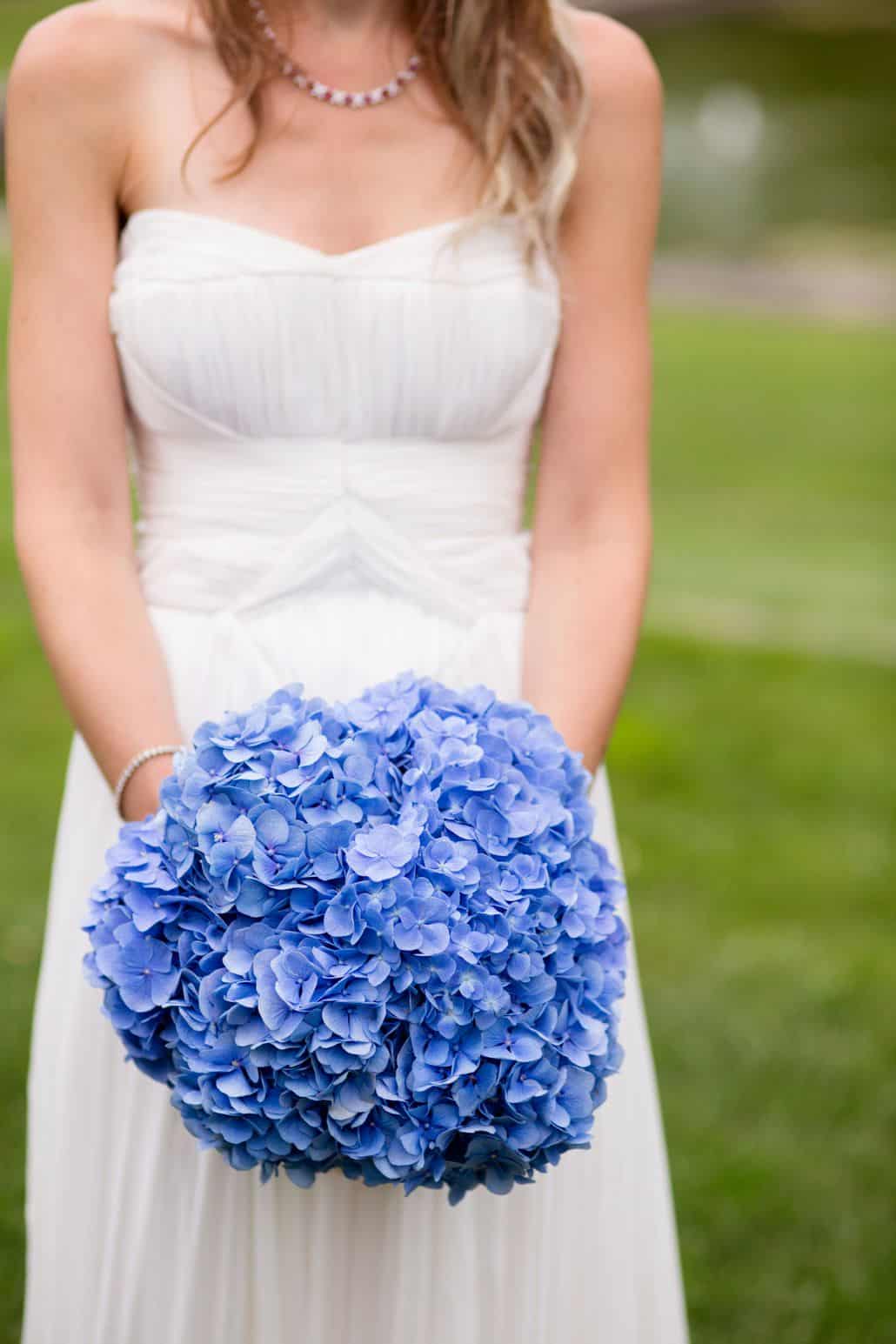 bride in strapless ruched wedding gown holds blue hydrangea wedding bouquet, Viburnum florist, Jasna Polana wedding, Princeton, NJ wedding photographer.