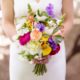 bride holds colorful mixed bouquet of purple, pink, fuscia, yellow and white flowers, peony, ranunculus, Y necklace, Molly Oliver florist, Invisible Dog Art Center, NYC wedding photographer.