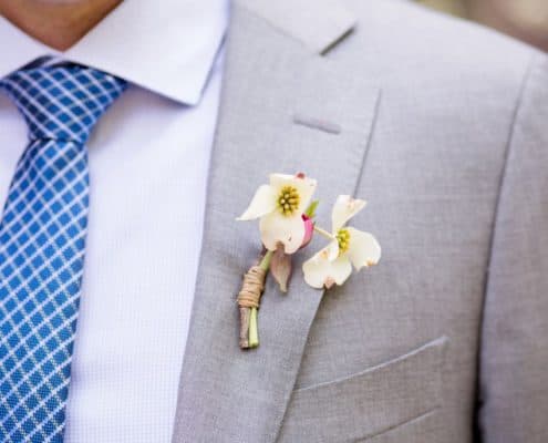 Tiny white flowers boutineer wrapped with raffia, light gray suit, blue and white small plaid tie, Molly Oliver florist, Invisible Dog Art Center, NYC wedding photographer.
