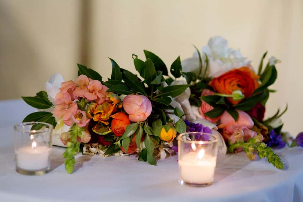 wedding table centerpiece with clear votive holders, mixed floral bouquet, peach, orange, purple, yellow, tulips, roses, snap dragon, ranunculus, Molly Oliver florist, Invisible Dog Art Center, NYC wedding photographer.