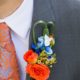 orange and blue boutinneer wrapped with navy ribbon, roses, glossy green grassy accents, groom wears gray suit, blue and orange paisley tie, Whole Foods florist, Cap and Gown Club, Princeton ,NJ wedding photographer.