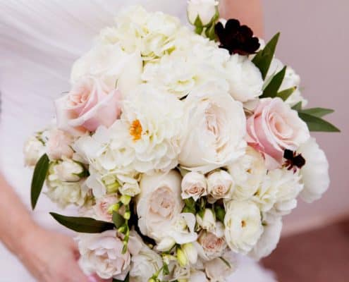 bride holds large pale pink and white wedding bouquet with dark green leaf accents, roses, zinnias, hydrangea, Viburnum florist, Cherry Valley Country Club, Skillman, NJ wedding photographer.