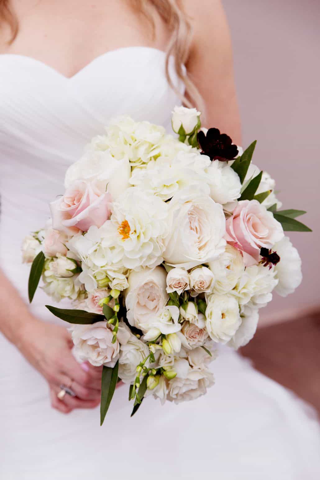 bride holds large pale pink and white wedding bouquet with dark green leaf accents, roses, zinnias, hydrangea, Viburnum florist, Cherry Valley Country Club, Skillman, NJ wedding photographer.