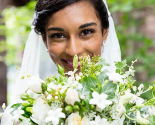 bride smiles looking over green and white wedding bouquet. Wildflowers of Princeton Junction florist, Mercer Oaks Country Club, Princeton Junction, NJ wedding photographer.