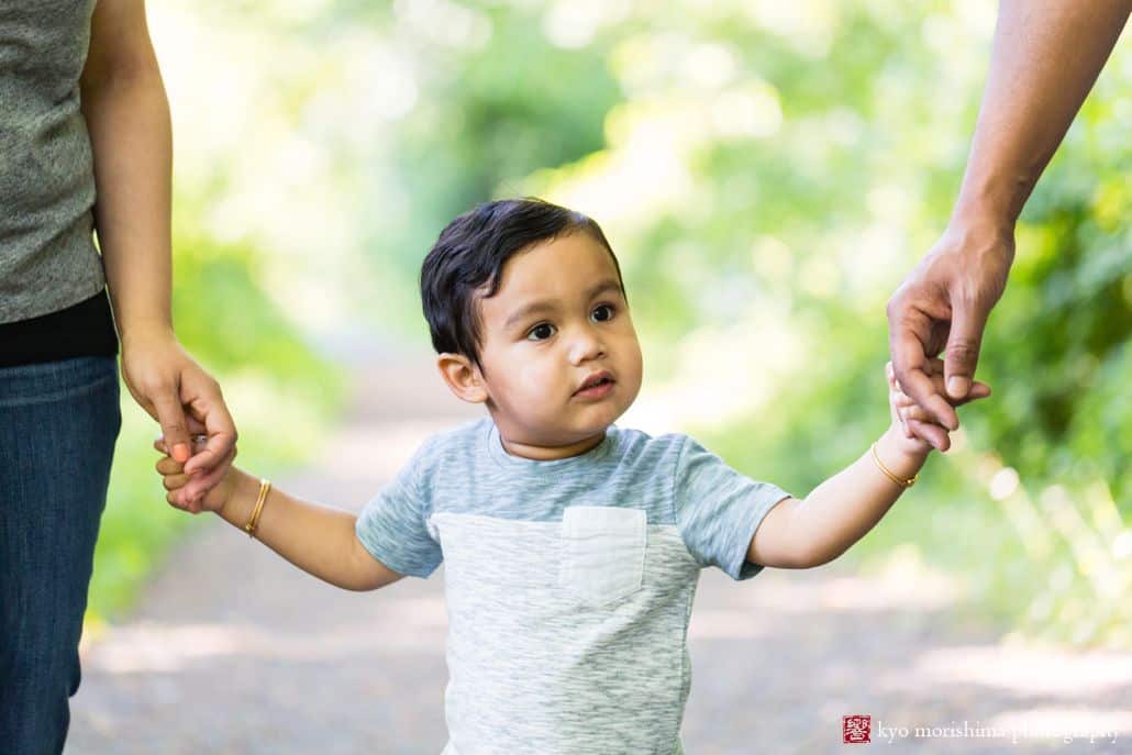 Candid kids photographer in Princeton: young boy holding parents hands in Battlefield Park