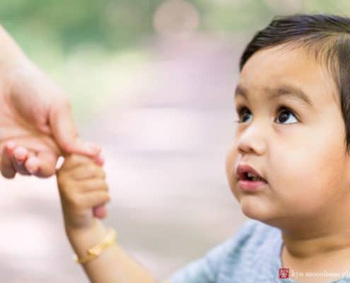 Family photojournalism photographer NJ: little boy holds is mother's finger and looks up at her