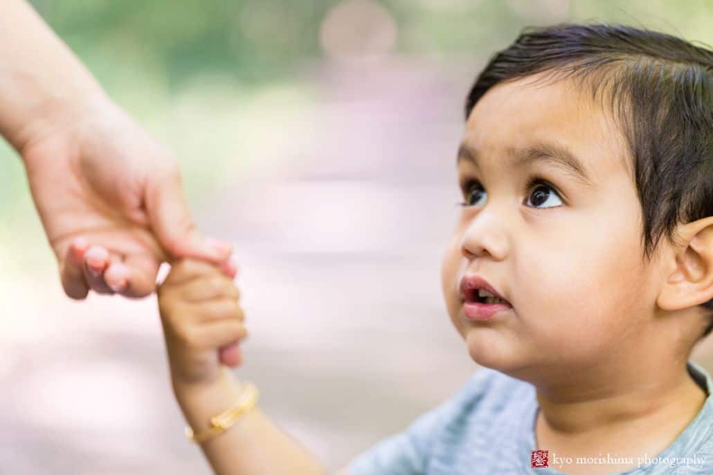 Family photojournalism by Princeton kids photographer Kyo Morishima: little boy holds is mother's finger and looks up at her