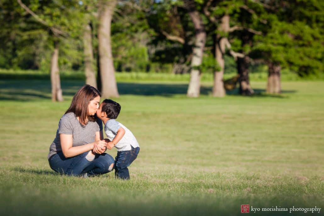 Documentary family photographer, NJ: little boy gives mom a kiss as they play in Battlefield Park