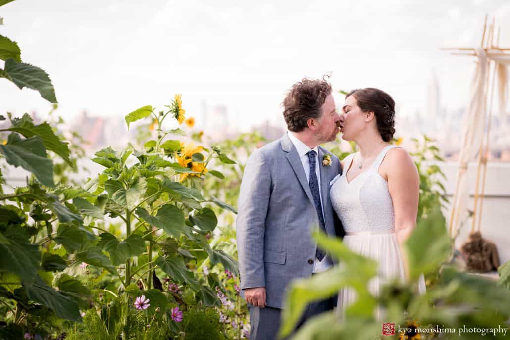 Brooklyn Grange wedding photos with sunflowers in the foreground as bride and groom kiss