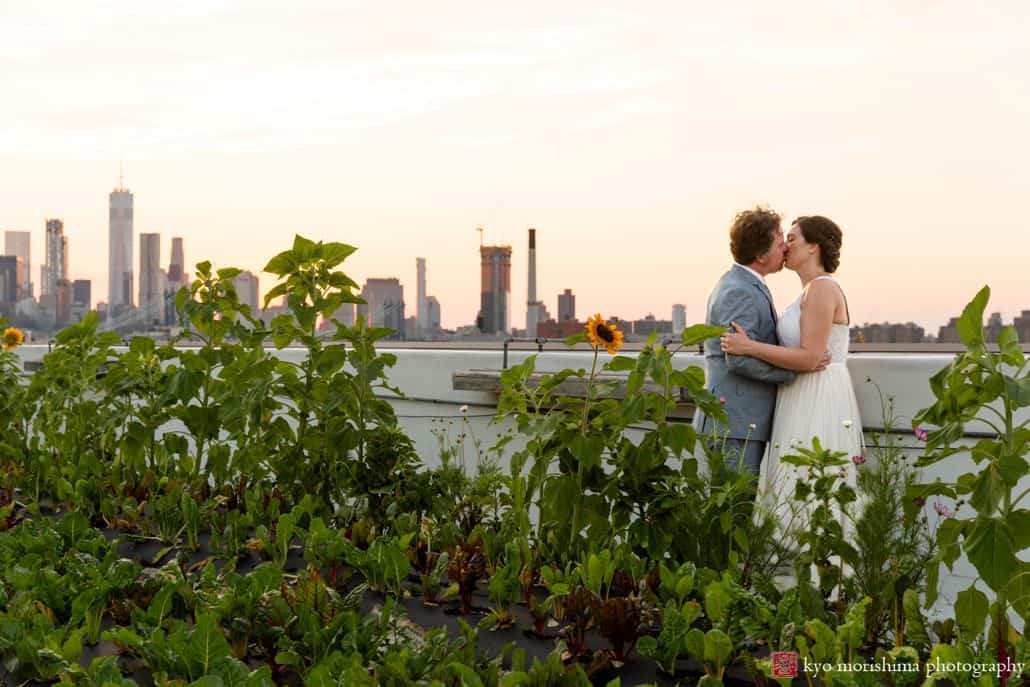 Bride and groom rooftop kiss during Brooklyn Grange wedding celebration in summer