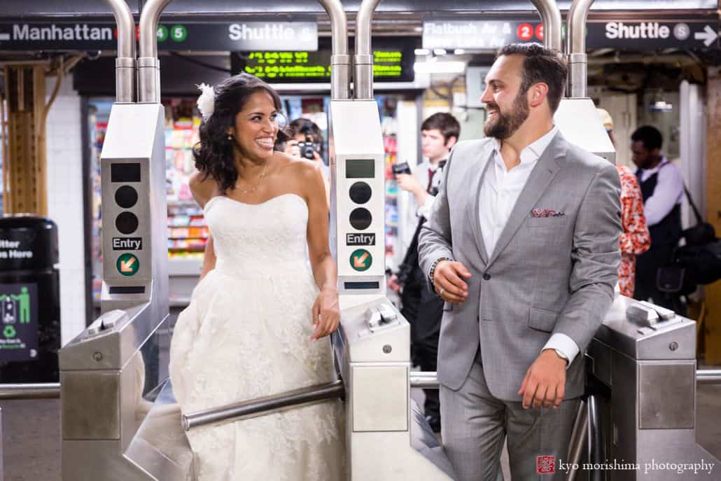 NYC subway wedding photo: bride and groom smile at each other as they walk through the MTA turnstile