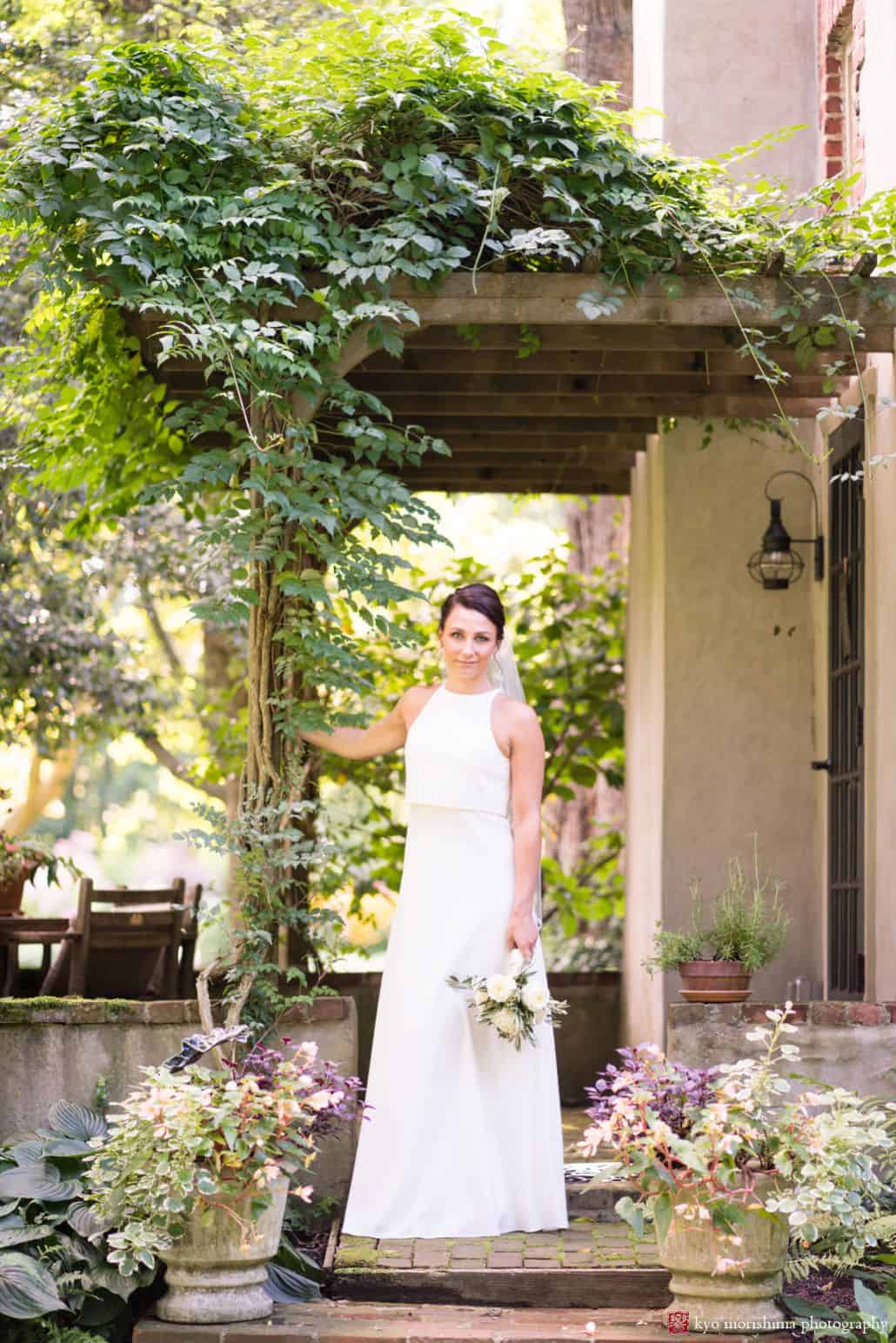 Portrait of bride under vine covered pergola holding white rose bouquet, BHLDN wedding dress, The Pod Shop Flowers, August New Hope, PA wedding photographer.