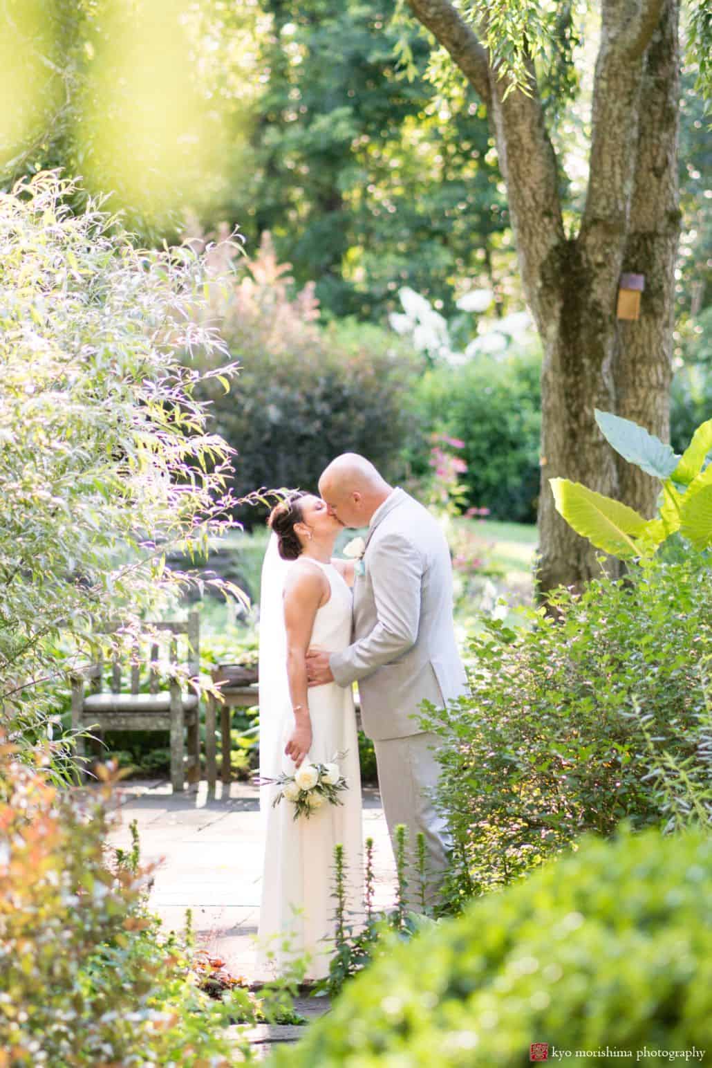 Bride and groom kiss in garden in New Hope, PA, The Pod Shop Flowers rose bouquet, Summer wedding photographer, intimate wedding.