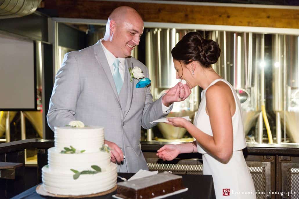 Groom feeds bride cake at Triumph Brewing Co, New Hope, PA, chocolate rectangular groom's cake, Factory Girl Bake Shop, BHLDN wedding dress, Men's Warehouse suit, teal tie and pocket square, intimate wedding photographer, triumph brewery wedding photos.